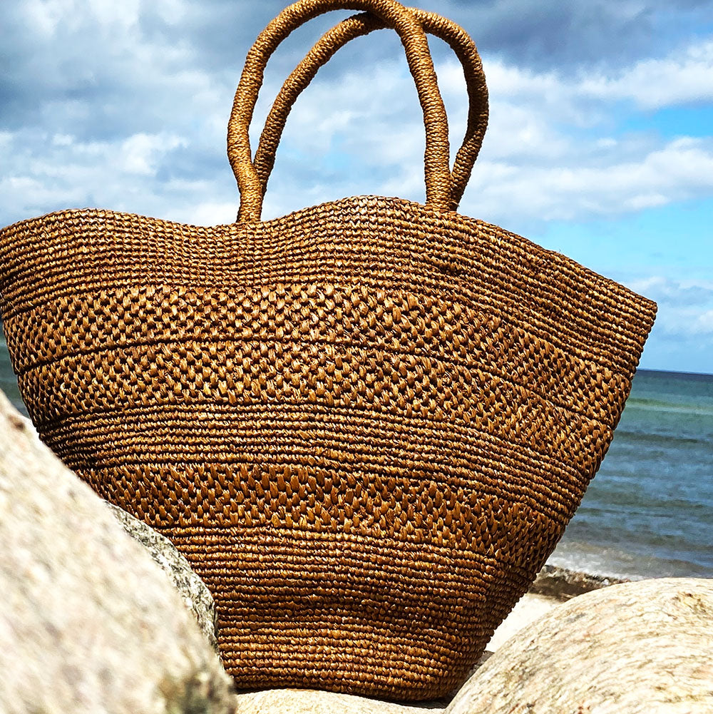 Anakao, the charming bag fashioned from luxurious raffia sourced from Madagascar. Tailored for your everyday adventures, this tote boasts a spacious main compartment to accommodate all your necessities while you're on the move. Raffia, derived from the resilient leaves of the palm tree, is celebrated for its versatility and eco-conscious qualities, making it a sought-after material in the realm of fashion accessories.