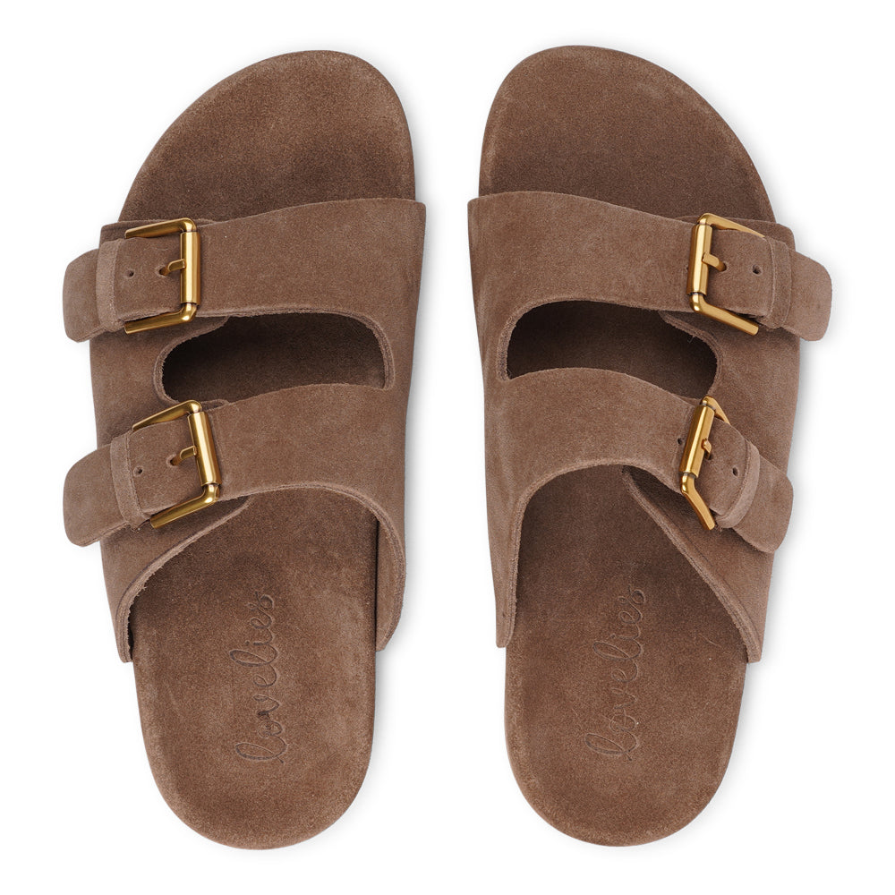 Lovelies Studio - Effortlessly laid-back with a touch of understated luxury, these suede sandals are designed for all-day comfort and timeless appeal. Crafted from rich, soft suede, they feature two wide straps with adjustable gold-tone buckles for a customizable fit. The contoured footbed offers light support, while the flexible sole ensures ease of movement from indoors to out.
Perfect for casual days, warm getaways, or everyday lounging in style.
Adjustable straps with metal buckles
Soft, cushioned foot
