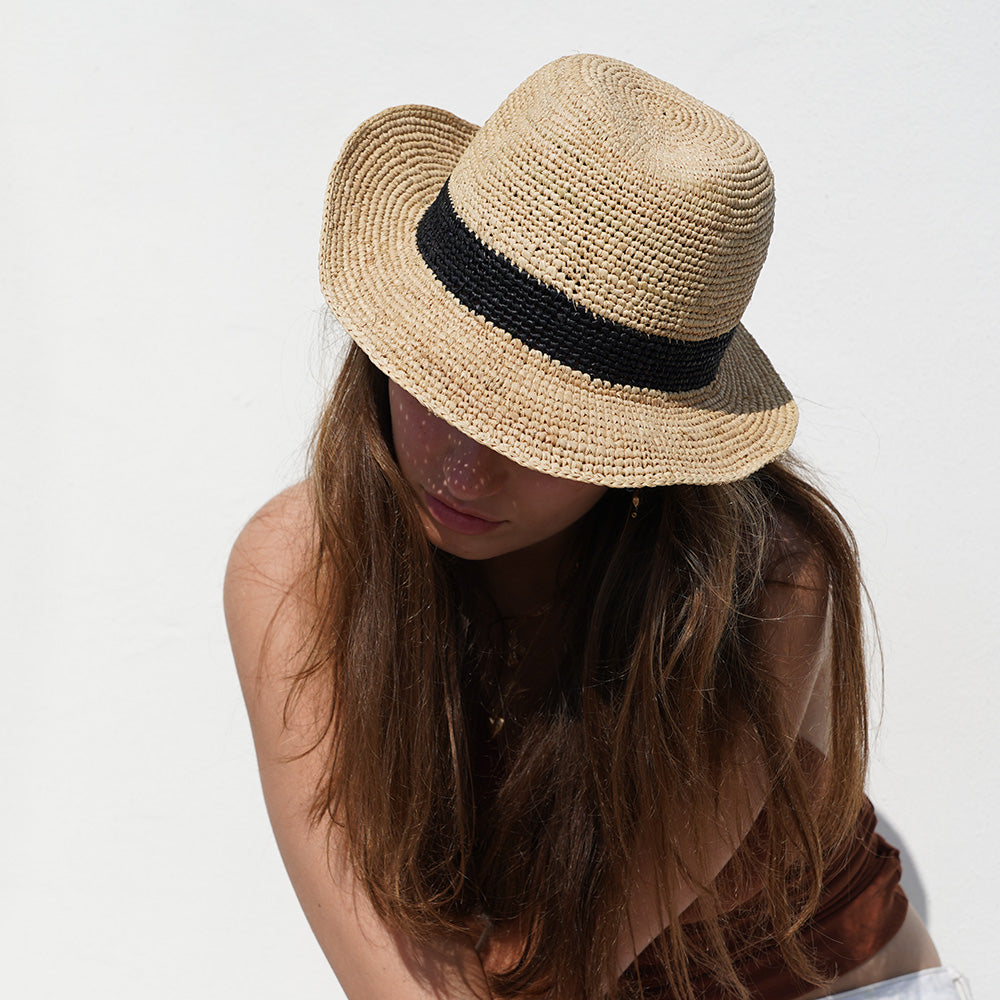 The Summery Viviani hat, a stunning creation meticulously crafted by local artisans in Madagascar exclusively for Lovelies Studio. Each piece is a testament to the skill and dedication of these artisans, who handcraft every detail with precision and care.  Made from raffia, a natural fiber renowned for its durability and flexibility, the Viviani hat is not only stylish but also eco-friendly. The raffia is carefully colored by hand using traditional methods