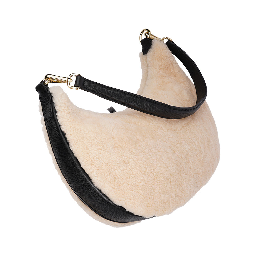 Kangmar is a beautiful shearling handbag which is perfect for carrying your essentials with you, it comes with detachable shoulder strap in skin. Top double zipped closure. Top handle in soft skin with hardware in gold. Adjustable and detachable shoulder strap in leather, 15 mm wide.  Satin lining and flat zipped inner pocket Item comes with a branded dust bag. Embossed Lovelies logo inside the bag.  Gold-toned hardware Measurements W36 X D5 X H20 cm 100 % Australian shearling 