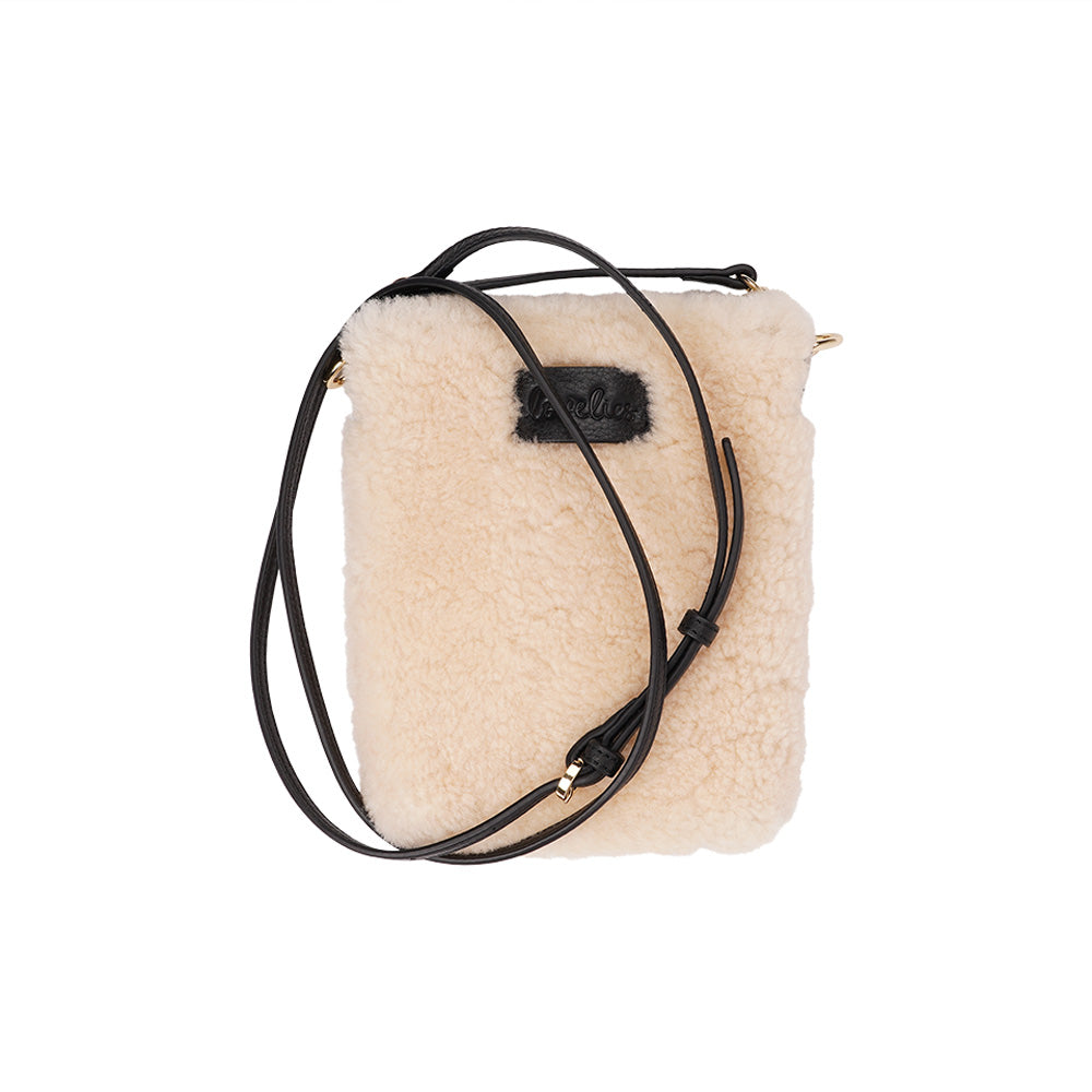 Lovelies studio Tingri is a handy cross shoulder phone bag, hand made from the finest curly shearling from Australia. * Top magnet closing * Adjustable and detachable 8 mm wide shoulder strap in leather * Skin lining and flat inner pocket * Item comes with a branded dust bag. * Embossed Lovelies logo on the front. * Gold-toned hardware * Measurements W12 X D4 X H17 cm * 100 % Australian curly shearling