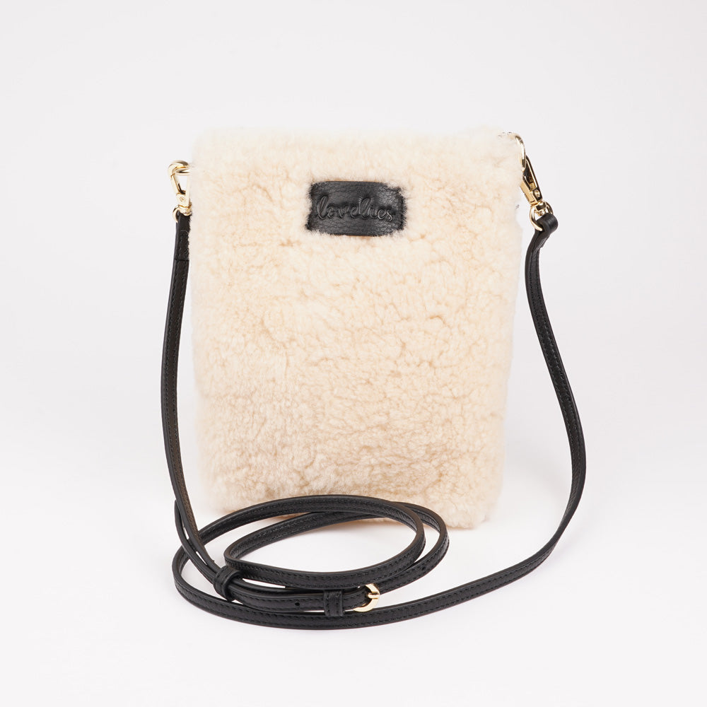 Lovelies studio Tingri is a handy cross shoulder phone bag, hand made from the finest curly shearling from Australia. * Top magnet closing * Adjustable and detachable 8 mm wide shoulder strap in leather * Skin lining and flat inner pocket * Item comes with a branded dust bag. * Embossed Lovelies logo on the front. * Gold-toned hardware * Measurements W12 X D4 X H17 cm * 100 % Australian curly shearling