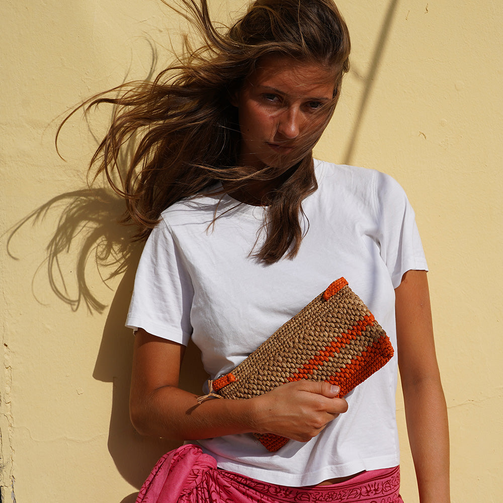 Meliso, the little charming clutch fashioned from luxurious raffia sourced from Madagascar.  Raffia, derived from the resilient leaves of the palm tree, is celebrated for its versatility and eco-conscious qualities, making it a sought-after material in the realm of fashion accessories.