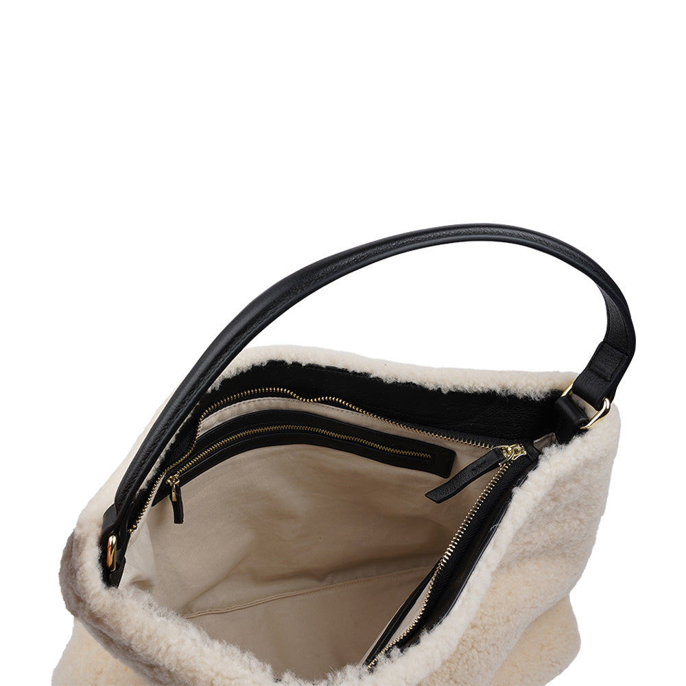 Mainling is a tribute to craftsmanship and the handmade, this large and very soft bag comes in curly shearling and with beautiful leather details. * Top double zipped closure. * Top handle in soft skin with hardware in gold. * Adjustable and detachable shoulder strap in leather, 15 mm wide. * Satin lining and flat zipped inner pocket * Item comes with a branded dust bag. * Embossed Lovelies logo on the front. * Gold-toned hardware * Messurements W40 X D10 X H30 cm * 100 % Australian shearling